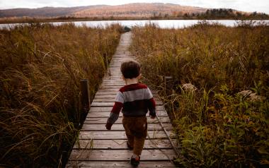a young child running on a boardwalk