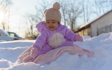 A smiling young child bundled up in winter clothes