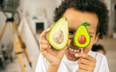 A concept photo of a child holding up two avocado halves