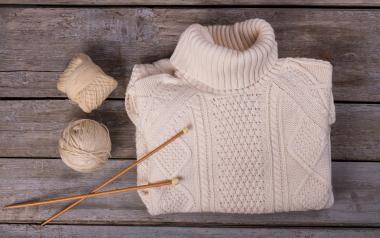 a folded knit sweater with yarn and knitting needles