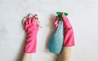 hands in rubber gloves holding a cleaning rag and spray