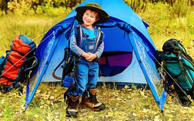 young boy standing in front of small blue tent