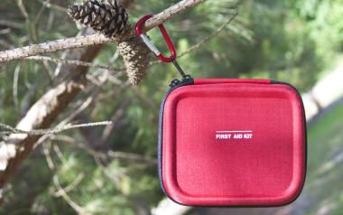 red first aid kit hanging on a tree branch