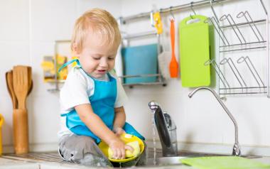 Cute child washing up in kitchen sink