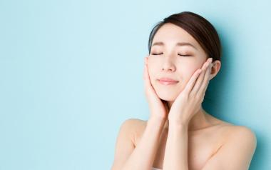 Facial Serums: Beautiful woman touching her face against a light blue background