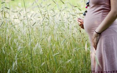 Techniques to manage labour pain: Pregnant woman standing in field of grass
