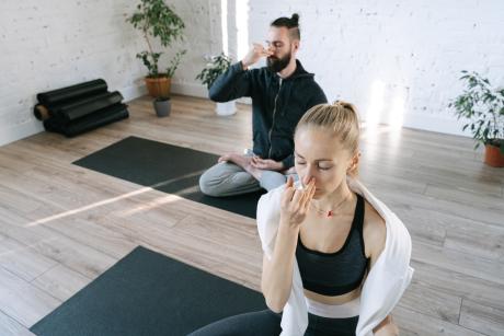 man and woman on yoga mats doing alternating nostril breathing exercise