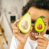 A concept photo of a child holding up two avocado halves