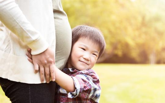 little boy hugging pregnant woman's belly