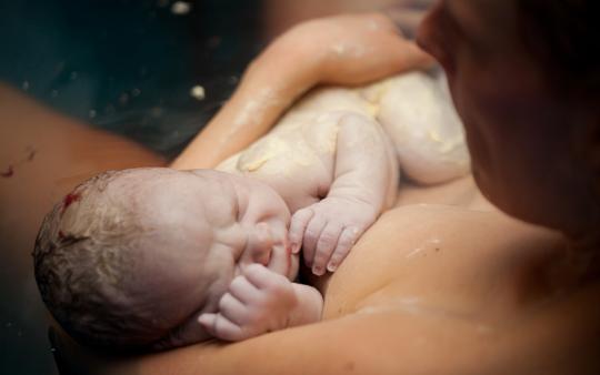 newborn baby being held by mother after waterbirth