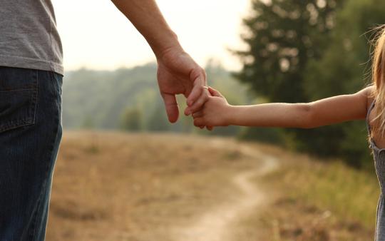 view of child's and parent's arms while holding hands