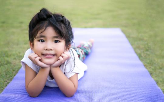 young girl lying on a blanket with her chin in her hands posing for the camera