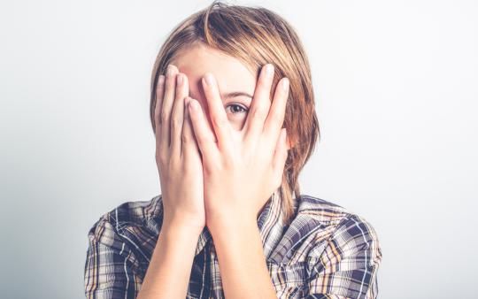 young child hiding behind their hands