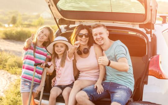 family sitting on back of open hatchback