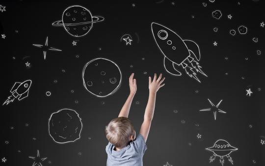 young child observing chalkboard drawings of space