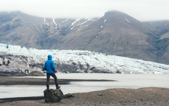 view of a person from behind looking at the snowy mountainous natural environment