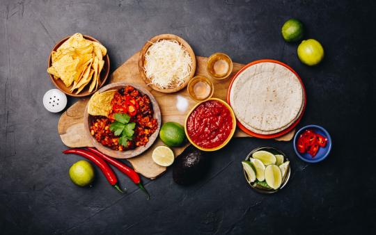 assorted taco ingredients laid out on black background