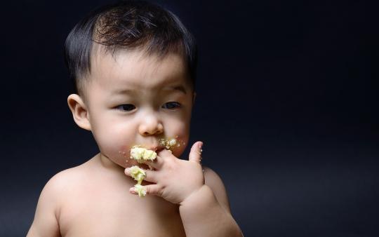 baby eating messy food off fingers