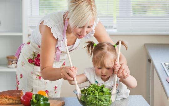 mom helping toddler toss salad