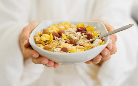 A white cereal bowl with corn flakes and berries 