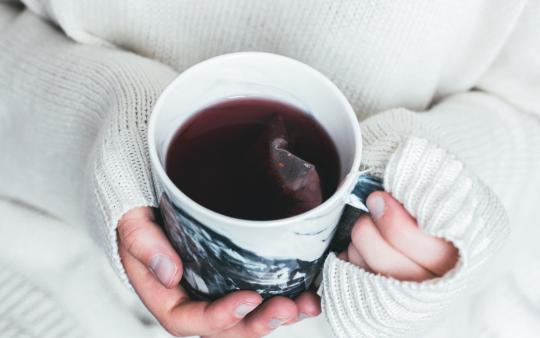 A woman holding her hands around a tea cup