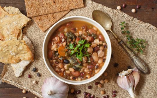 a hearty bowl of bean soup with a spoon on a table