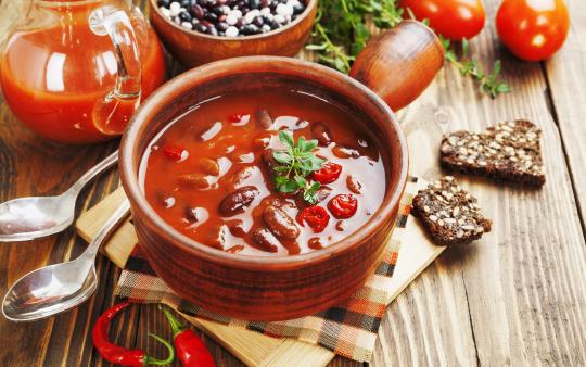 a bowl of chili on a table with spoons