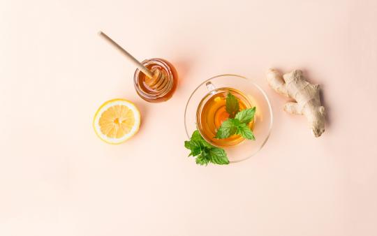 cup tea, piece of ginger, a half lemon and a small glass with honey and a stir stick