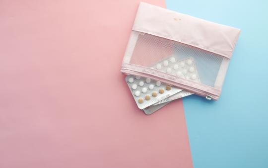 two packages of small circular pills and a pill pouch