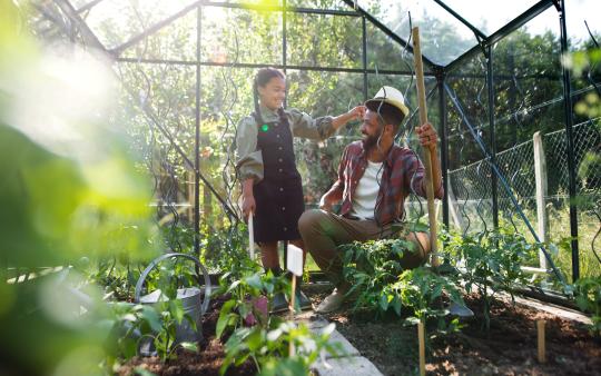 father and daughter in a green house surrounded by plants