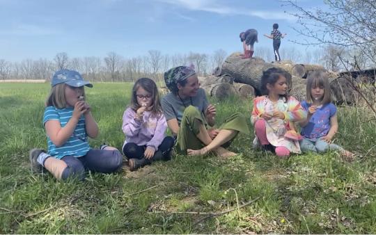 Children and a mother sit on the grass