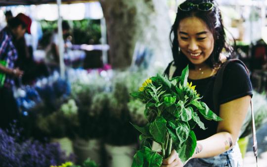 woman smiles holding a plant 