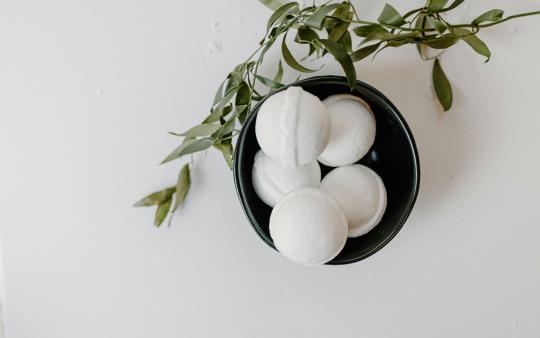 Bath bombs in a bowl next to leaves