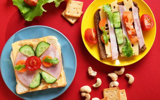 two plates of colourful sandwiches on plates with snacks in the background