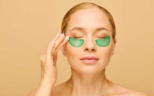 a woman with green cooling under eye patches for self care