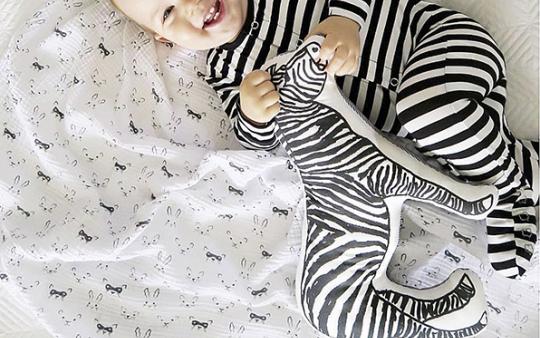 a baby in a black and white striped onesie romper 