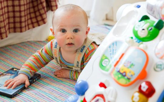 Simple and Fun Baby Games: baby laying on stomach surrounded by toys