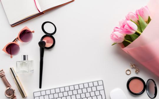 assorted items on a white table, pink flowers, make-up, keyboard, sunglasses