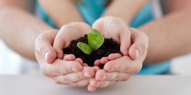 Self-watering seed starter in a Recycled Bottle: parent and child holding seedling together