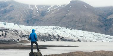 view of a person from behind looking at the snowy mountainous natural environment