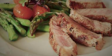 roasted meat, asparagus and tomatoes on a plate