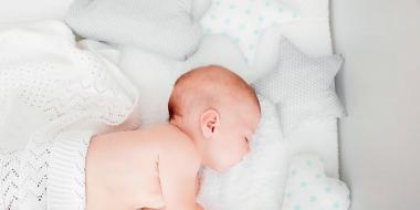 baby sleeping under white blanket