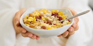 A white cereal bowl with corn flakes and berries 