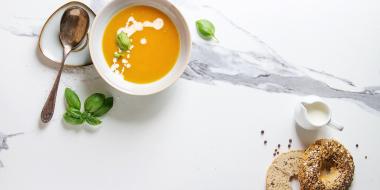 carrot soup in a bowl, a spoon and an everything bagel