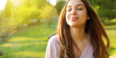 woman outside taking a deep breath in with eyes closed