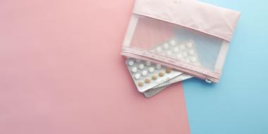 two packages of small circular pills and a pill pouch