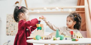 two little girls playing with blocks at a table