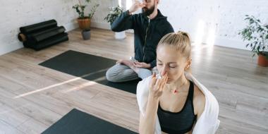 man and woman on yoga mats doing alternating nostril breathing exercise