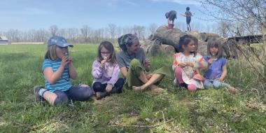 Children and a mother sit on the grass