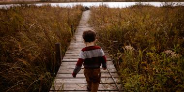 a young child running on a boardwalk